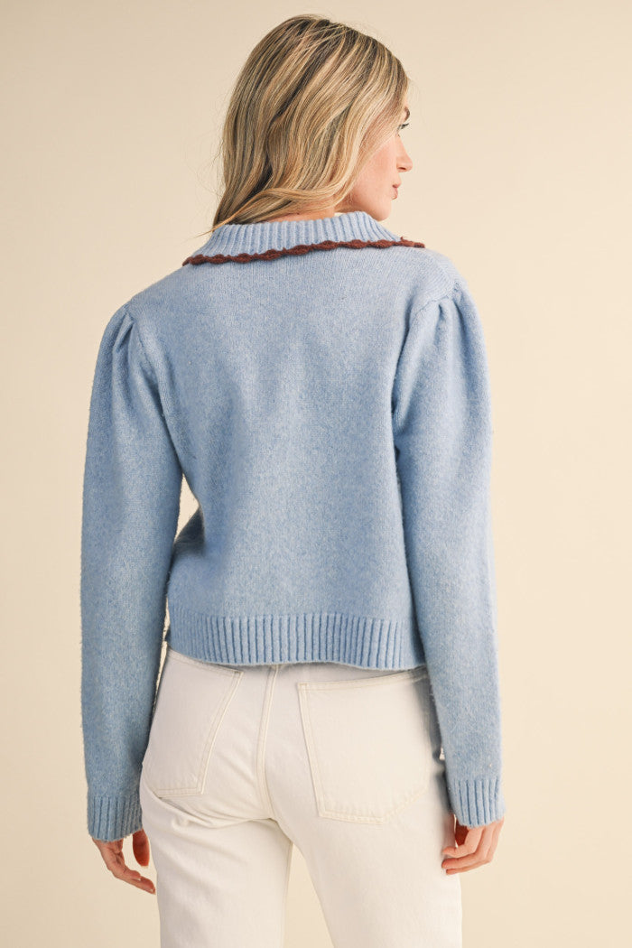 Set yourself up for a posh & cozy day in this scalloped collar sweater cardigan! Cozy knit shapes this must-have cardigan that has a ribbed collar neckline accented with scalloped edges in a contrast knit color. Gathered puff shoulders flow into long sleeves with ribbed cuffs. Covered, functional buttons adorn the front of the relaxed bodice