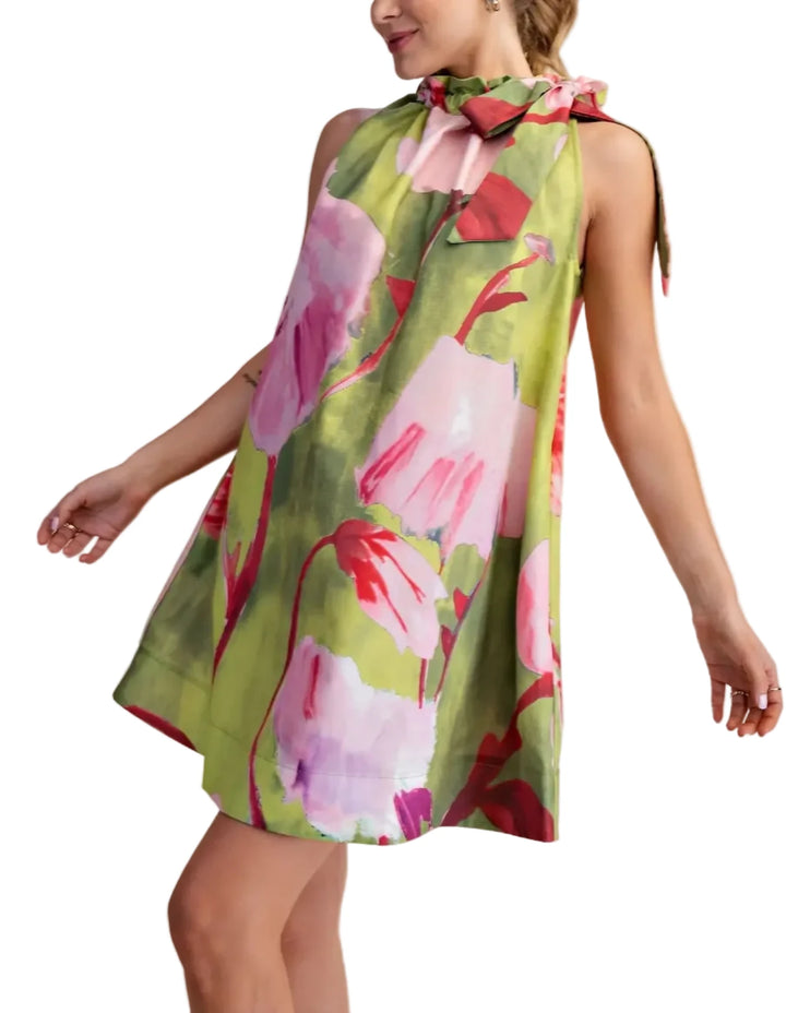 Woman wearing a floral dress with pink and green colors on a beige background