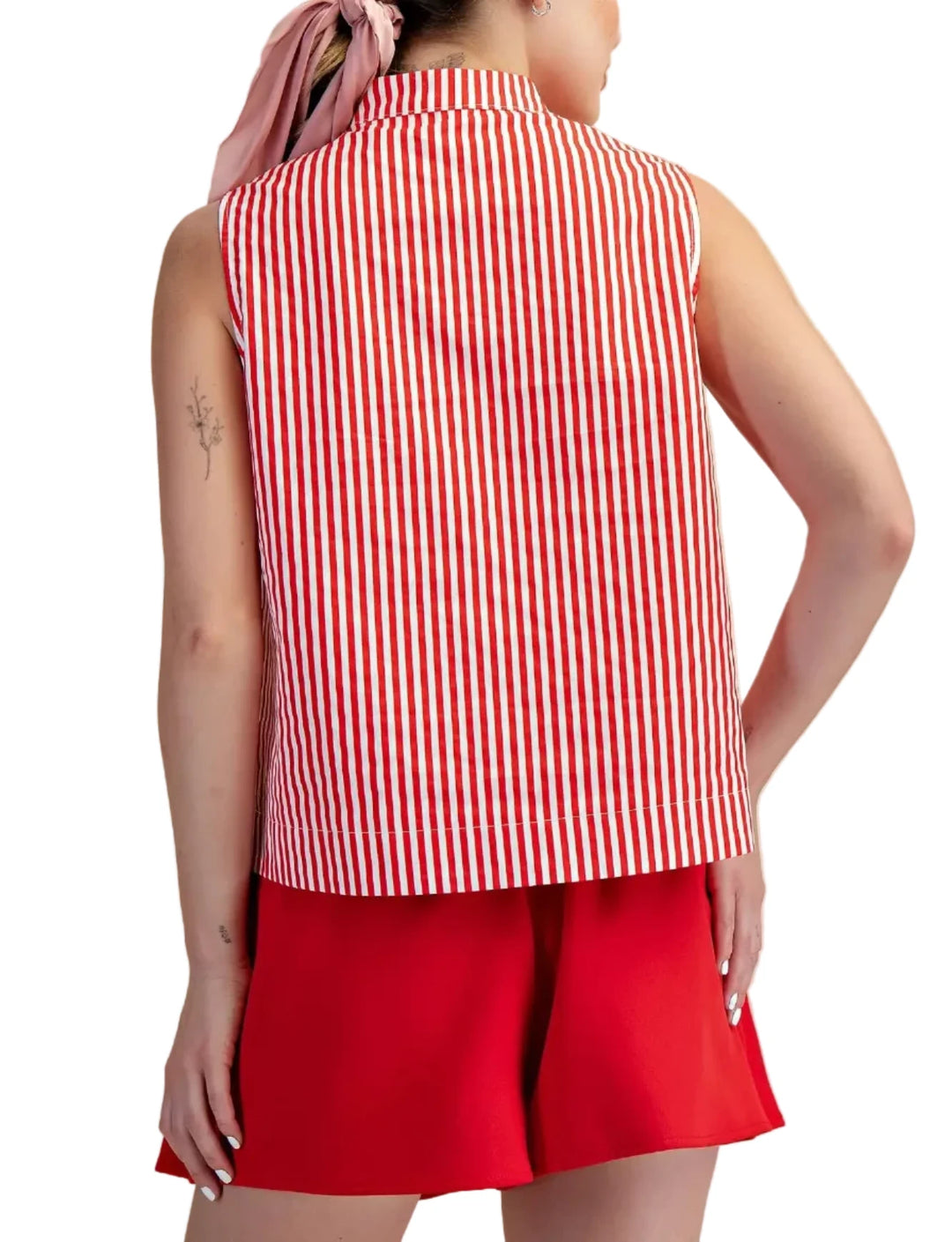 Woman wearing a red and white striped sleeveless shirt and red shorts on a beige background