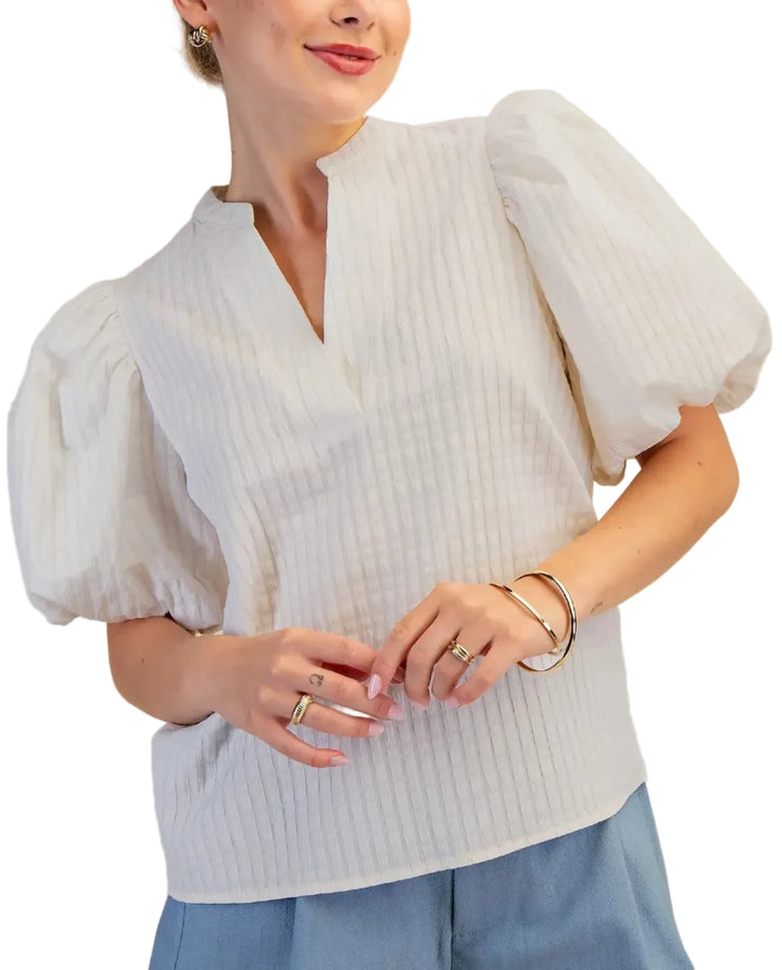 Elevate your wardrobe with this stunning puff sleeve top, designed to make a statement. Featuring dramatic puff sleeves and a unique waffle textured fabric, this blouse offers a sophisticated yet modern silhouette. The flattering V-neckline with a subtle keyhole detail adds a touch of allure, while the short sleeves provide comfort and ease of movement. Crafted from a high-quality material, this top drapes beautifully and feels as good as it looks. Perfect for dressing up or down, it pairs effortlessly with
