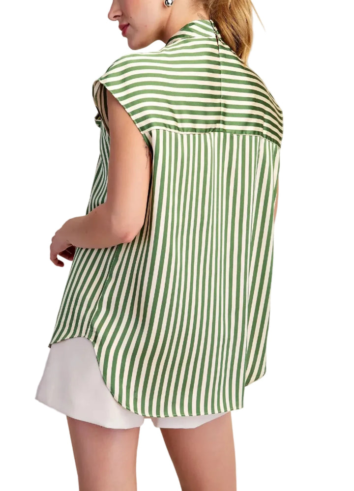 A woman shown from the back wearing a green and white vertically striped sleeveless blouse over a white skirt, against a plain beige studio background.