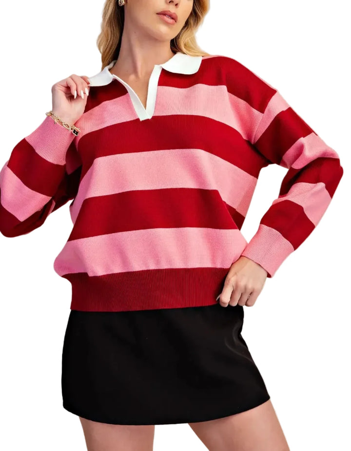 A woman wearing a pink and red horizontally striped rugby-style sweater with a white collar, paired with a black mini skirt, against a solid beige background.