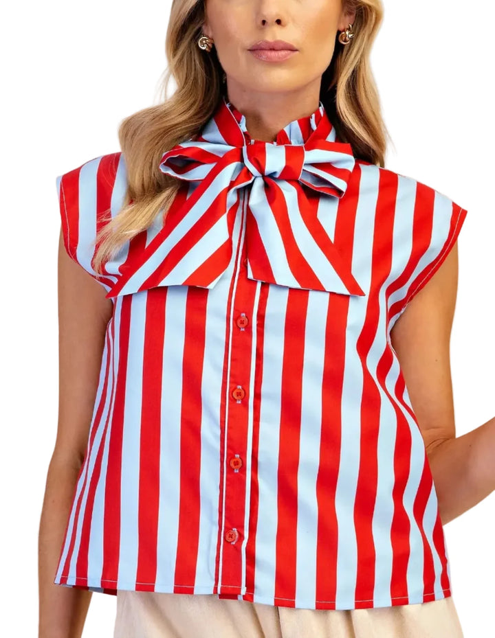 A woman wearing a sleeveless red and white vertically striped blouse with a large bow at the collar and front buttons, photographed against a plain beige studio background.