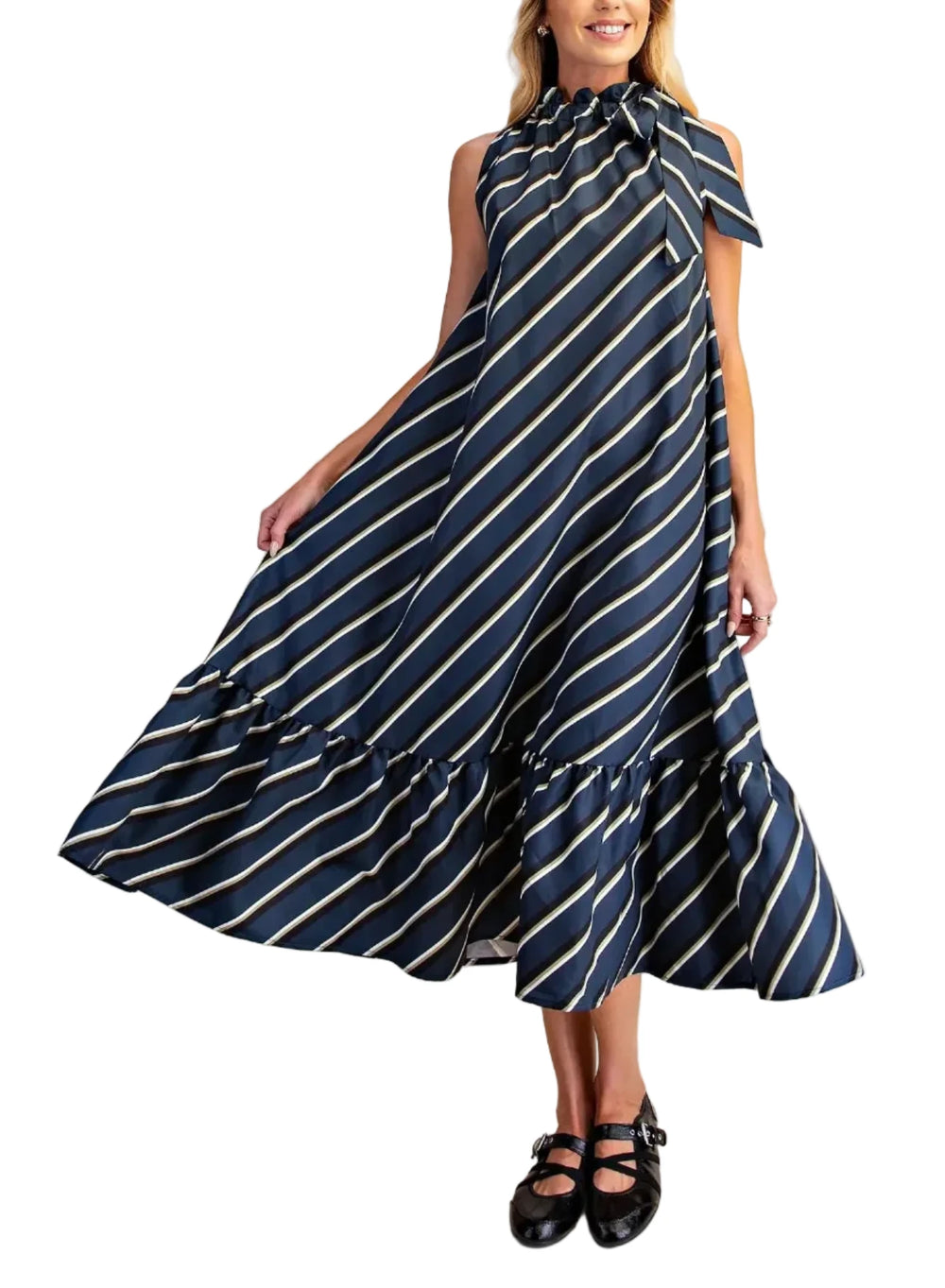 A woman modeling a sleeveless midi dress with a navy blue and white diagonal stripe pattern, a high ruffled collar, and a tiered skirt, set against a solid beige studio background.
