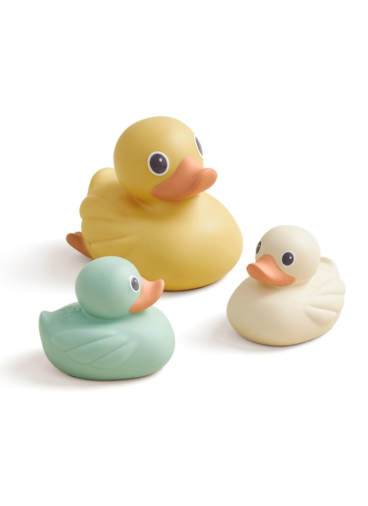 Three rubber duck toys in yellow, mint green, and cream, arranged on a clean white background.