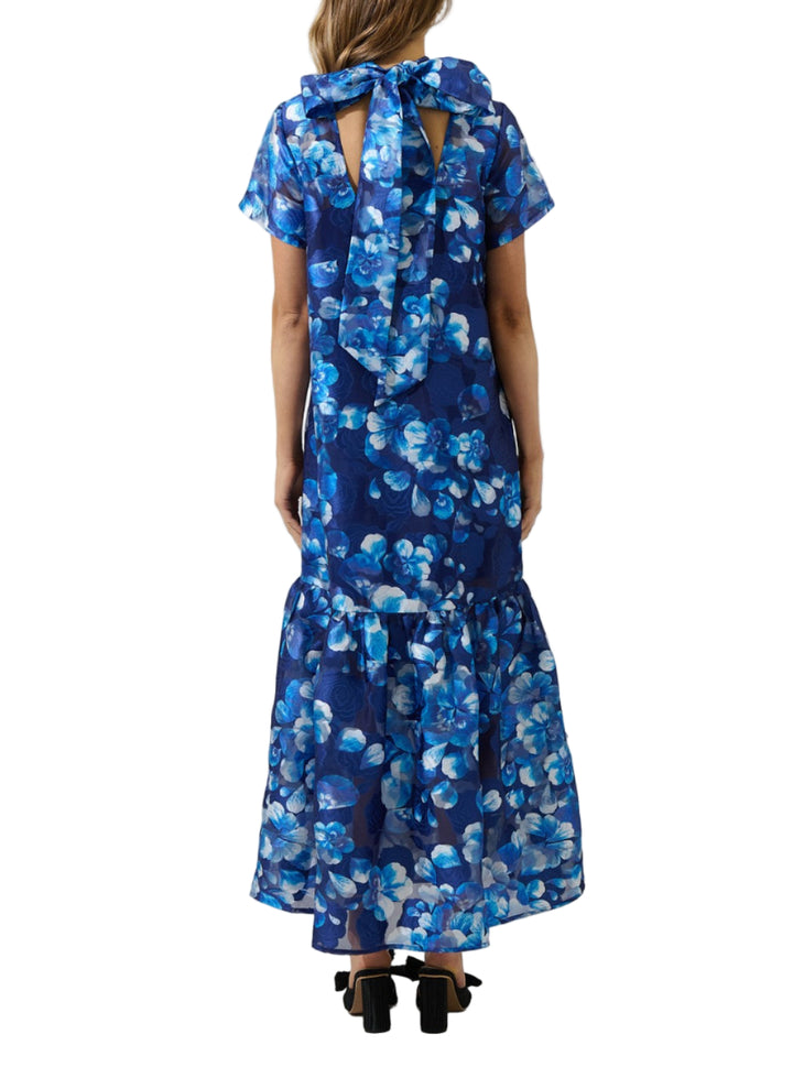 Woman wearing a blue floral dress against a plain background