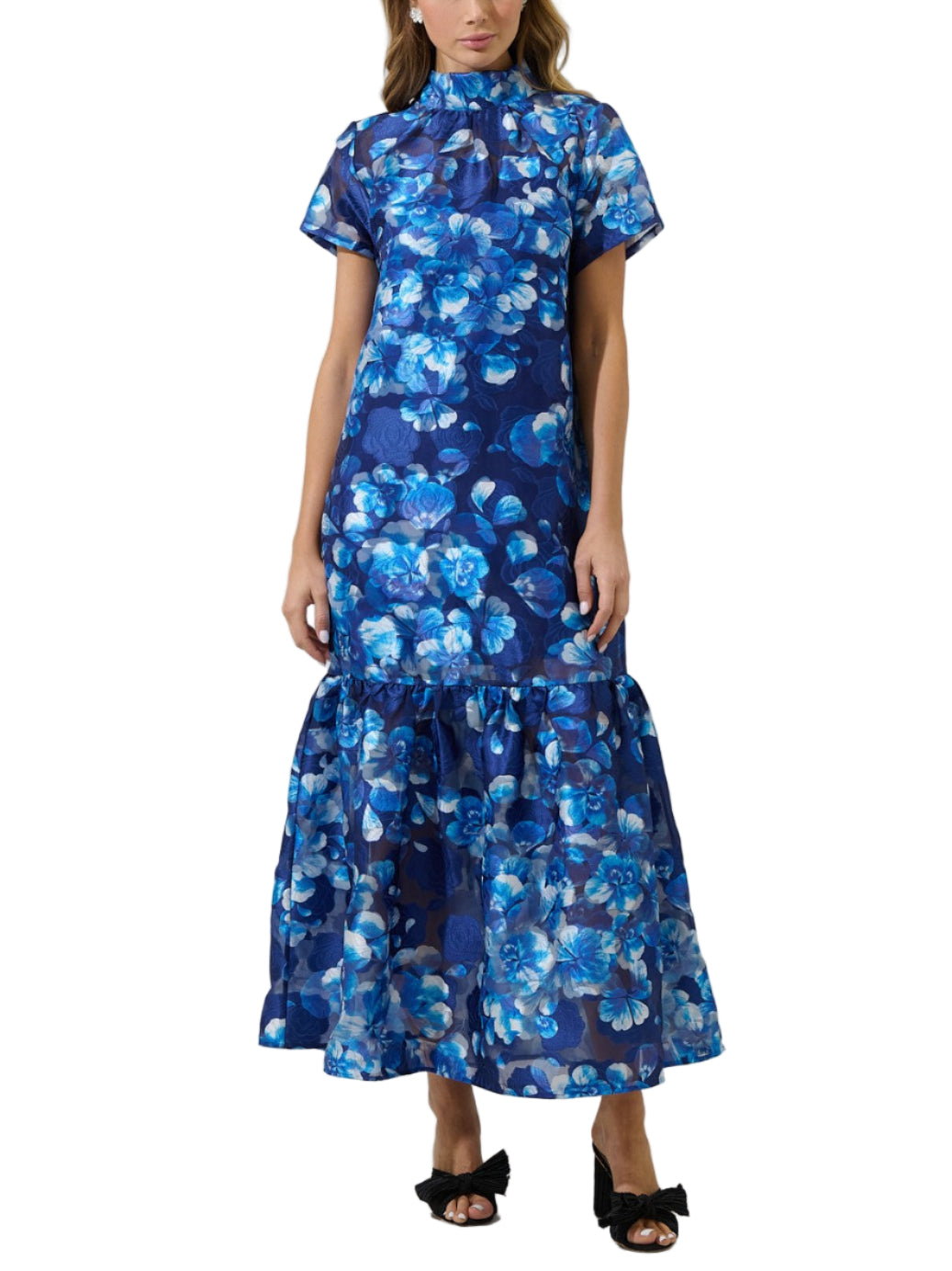 Woman wearing a blue floral dress against a plain background