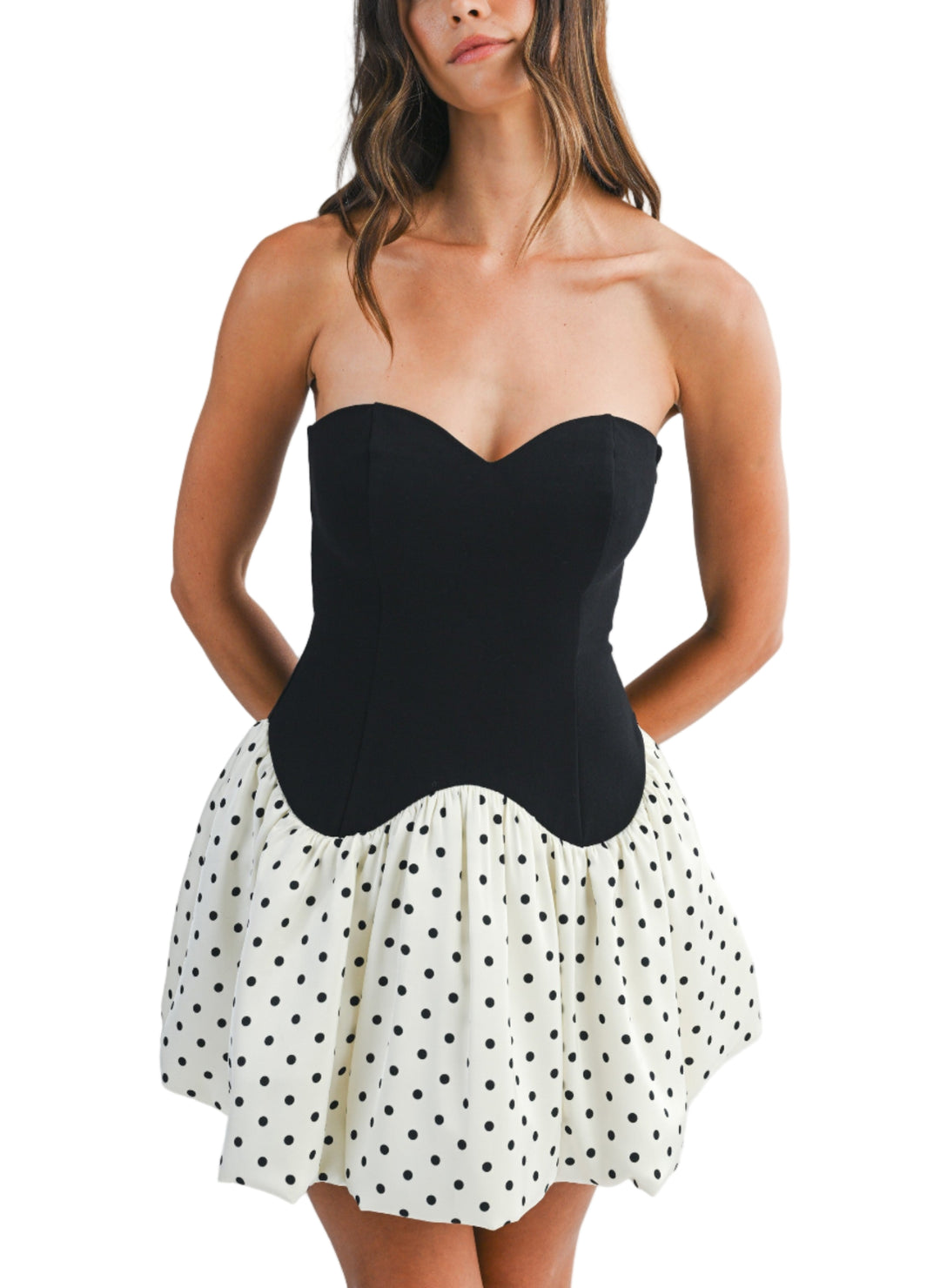 Woman wearing a strapless black top and polka dot skirt on a white background