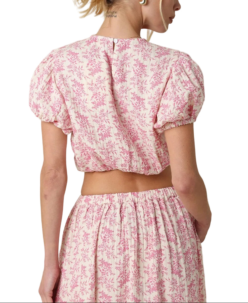 Twirl into spring with this adorable two-piece set featuring a cropped top with charming puff sleeves and an all-over pink floral print. The coordinating maxi skirt completes the look with the same delicate botanical design, creating a perfectly put-together outfit that&