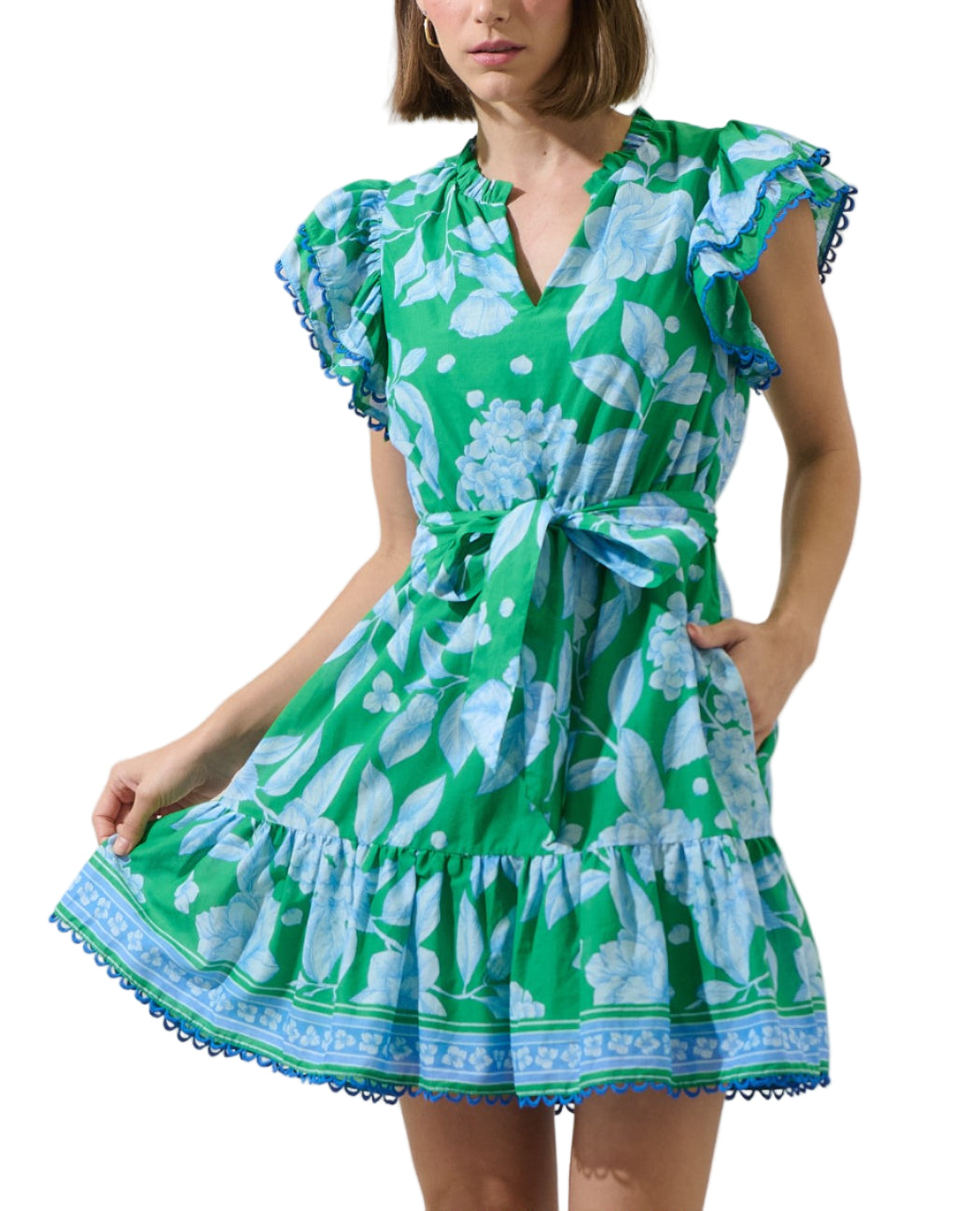 Breathe in the beauty of summer with this breezy Verbena Floral Eriny Ruffle Mini Dress. The dress features short layered sleeves that frame a v neckline. A belt around the waist can be adjusted and the bottom has ruffles