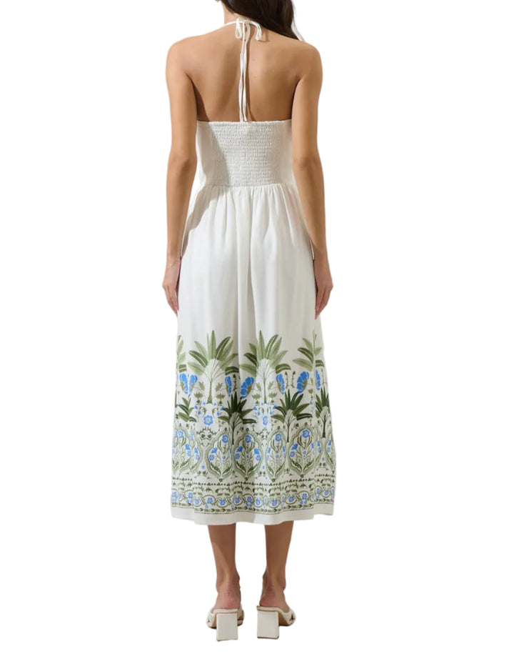 Easy to style and endlessly charming. A white midi length dress with a halter neck and a smocked bodice. It features a large, detailed border print, at the hem of the skirt. The back is open with adjustable tie back straps at the neck. Wear it with white heels.
