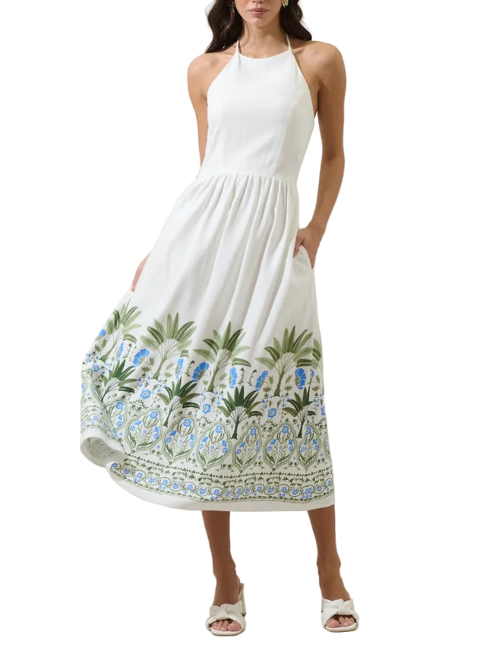 Easy to style and endlessly charming. A white midi length dress with a halter neck and a smocked bodice. It features a large, detailed border print, at the hem of the skirt. The back is open with adjustable tie back straps at the neck. Wear it with white heels.
