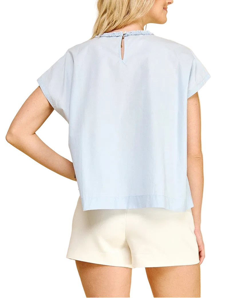 Woman wearing a light blue top and white shorts on a beige background