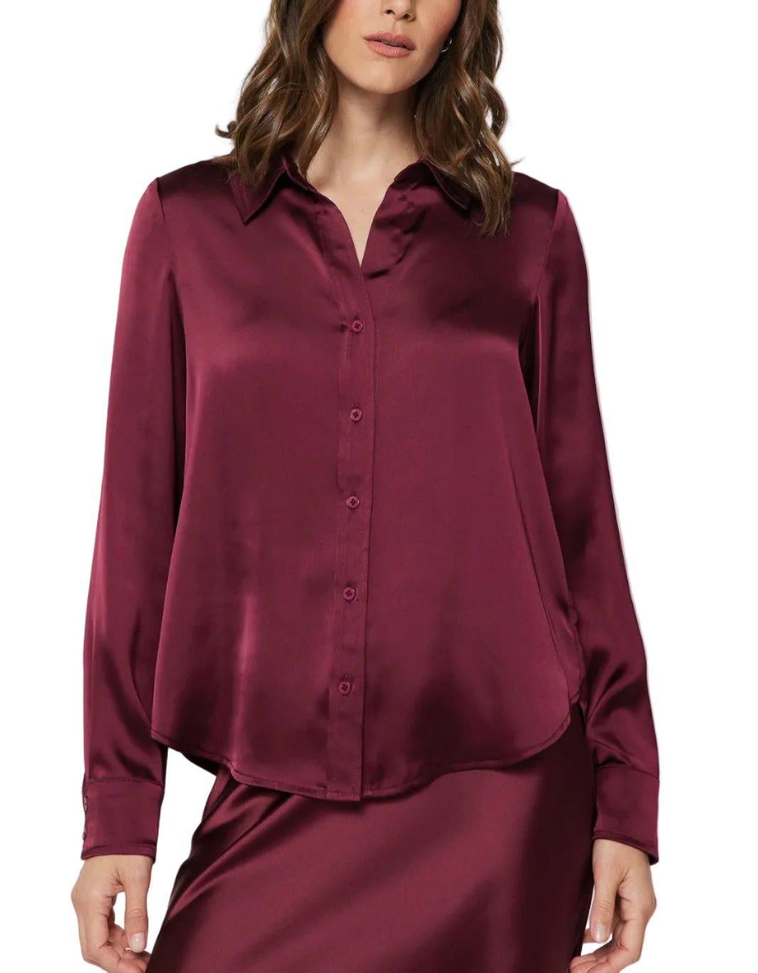 A woman wearing a long-sleeve satin button-up blouse in deep burgundy, paired with a matching satin skirt, against a light gray studio background.
