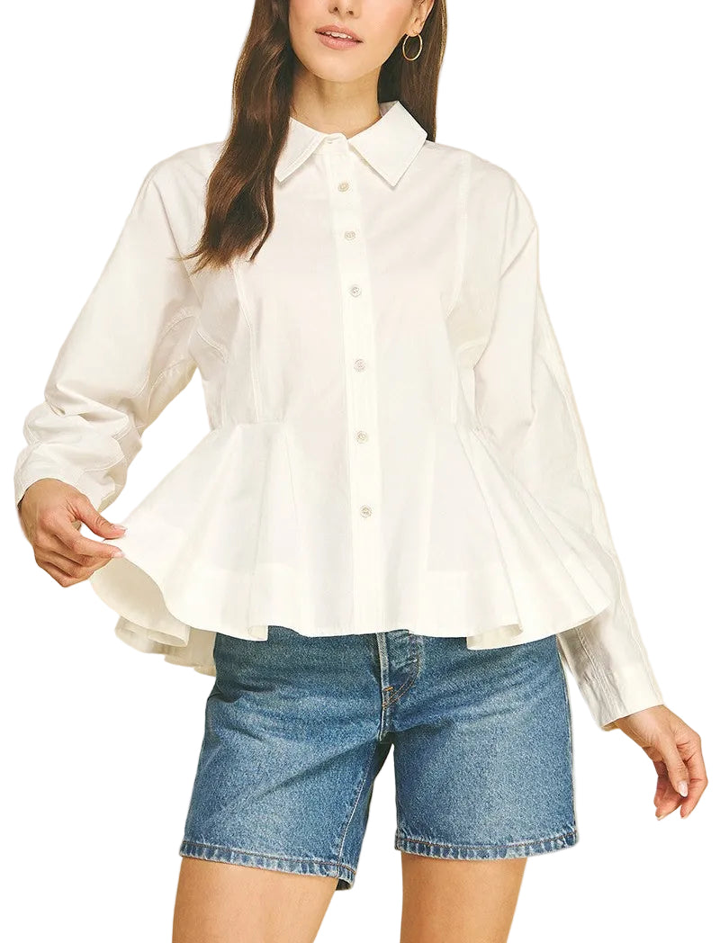 A woman modeling a white long-sleeve button-front blouse with a pointed collar and a peplum hem, paired with blue denim shorts, against a solid beige background.