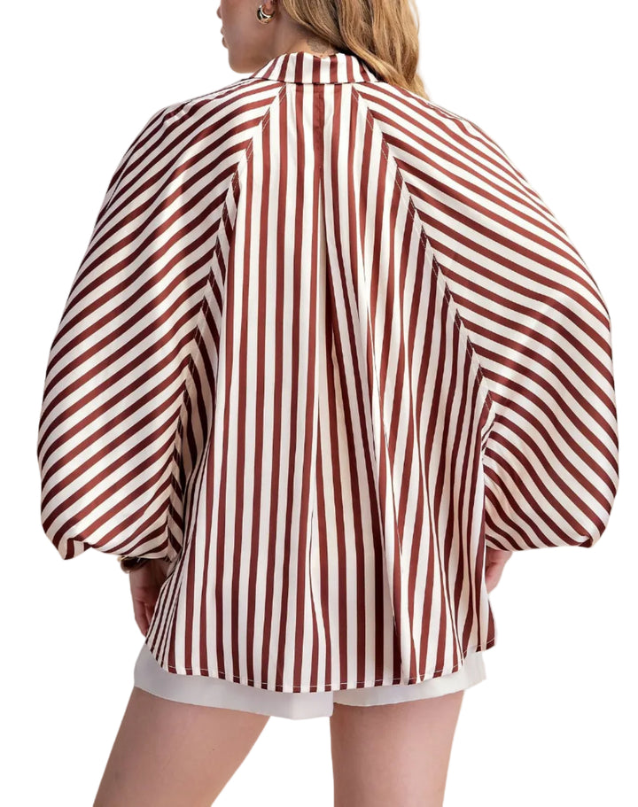 Elevate your wardrobe with this striking white striped shirt. Designed with a relaxed, oversized silhouette and voluminous long sleeves that gather at the cuff, this top offers both comfort and sophisticated style. The classic button-up front and crisp collar add a touch of timeless elegance, making it a versatile piece for any occasion. Crafted from a smooth, flowing fabric, this shirt drapes beautifully, creating a flattering and fashionable look. 