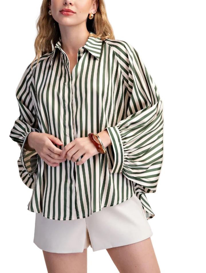Elevate your wardrobe with this striking white striped shirt. Designed with a relaxed, oversized silhouette and voluminous long sleeves that gather at the cuff, this top offers both comfort and sophisticated style. The classic button-up front and crisp collar add a touch of timeless elegance, making it a versatile piece for any occasion. Crafted from a smooth, flowing fabric, this shirt drapes beautifully, creating a flattering and fashionable look. 