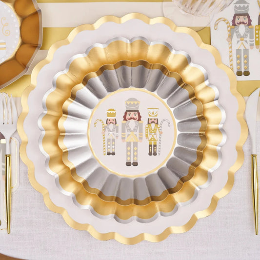 Featuring our signature scalloped edge plates adorned with elegant gold foil accents, this collection effortlessly blends modern style with timeless elegance. Showcasing classic nutcracker imagery in a sophisticated silver, gold, and white color palette, this tableware will add glitz and glam to your holiday meal.