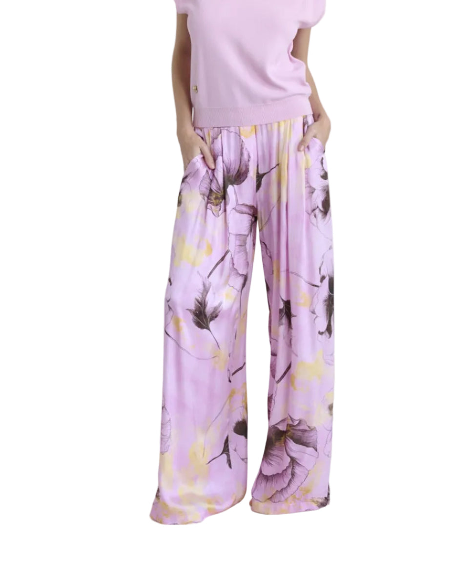 Woman wearing a pink outfit with floral pants on a white background