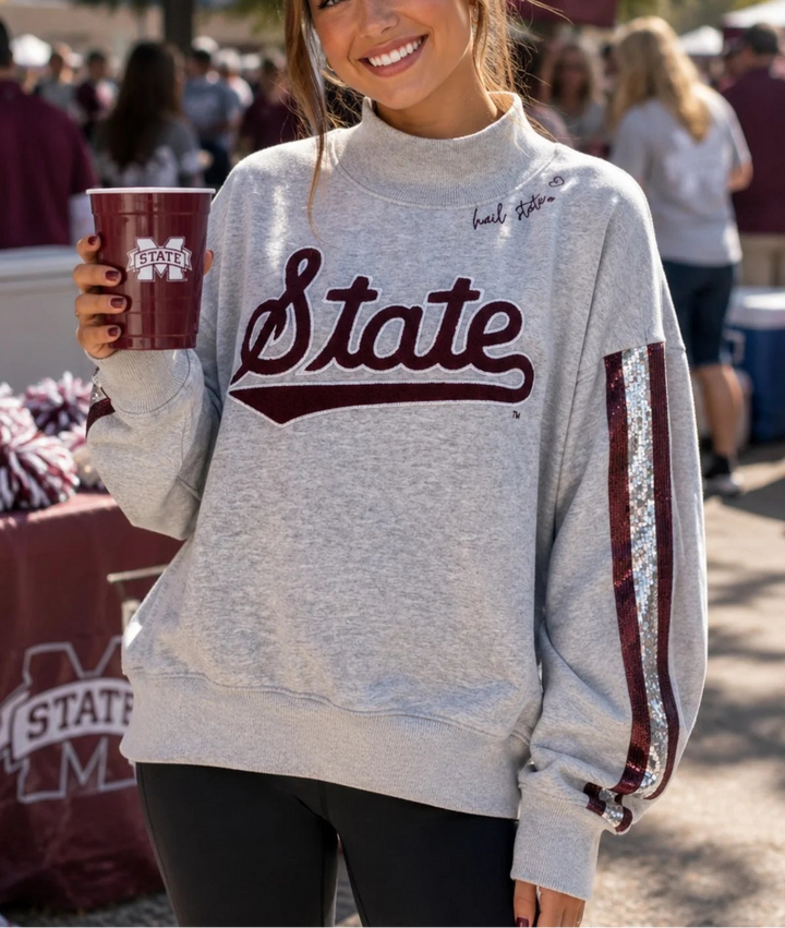 This is an Officially Licensed Collegiate Product
Soft gray mock neck sweatshirt featuring a bold Alabama elephant and “A” appliqué for a classic collegiate look
Eye catching sequin stripe detailing down each sleeve adds just the right amount of sparkle and contrast
Crafted from soft cotton Terry sweatshirt material 
Material: 80% Cotton, 20% Polyester
STYLE NOTE: This sweatshirt is made to fit oversized. You should purchase your normal size if you want the oversized look and fit. If you want a more fitted 