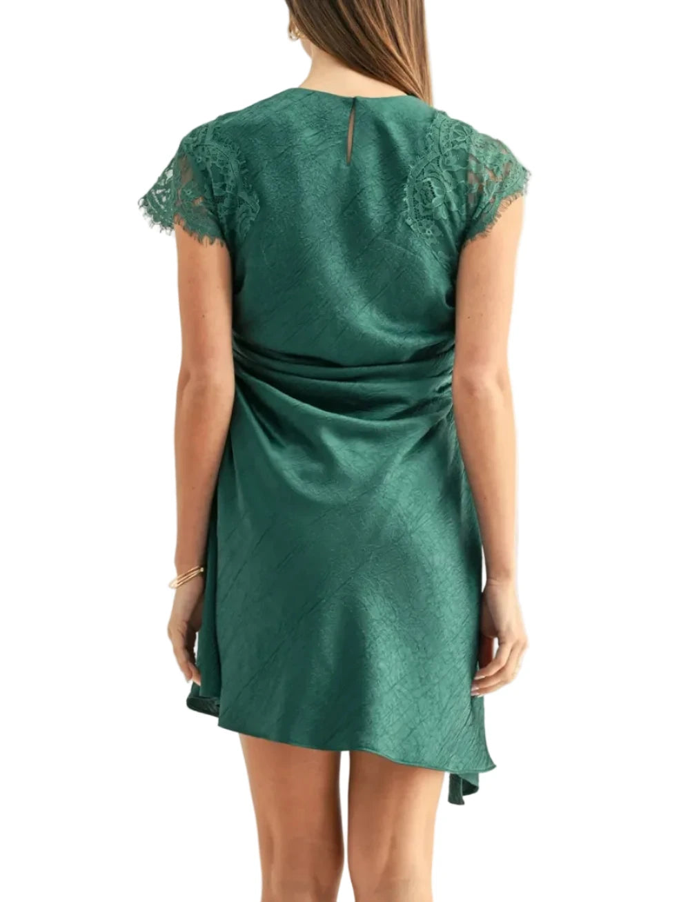A woman viewed from the back wearing a short green satin dress with lace cap sleeves and a gathered waist detail, against a plain light background.