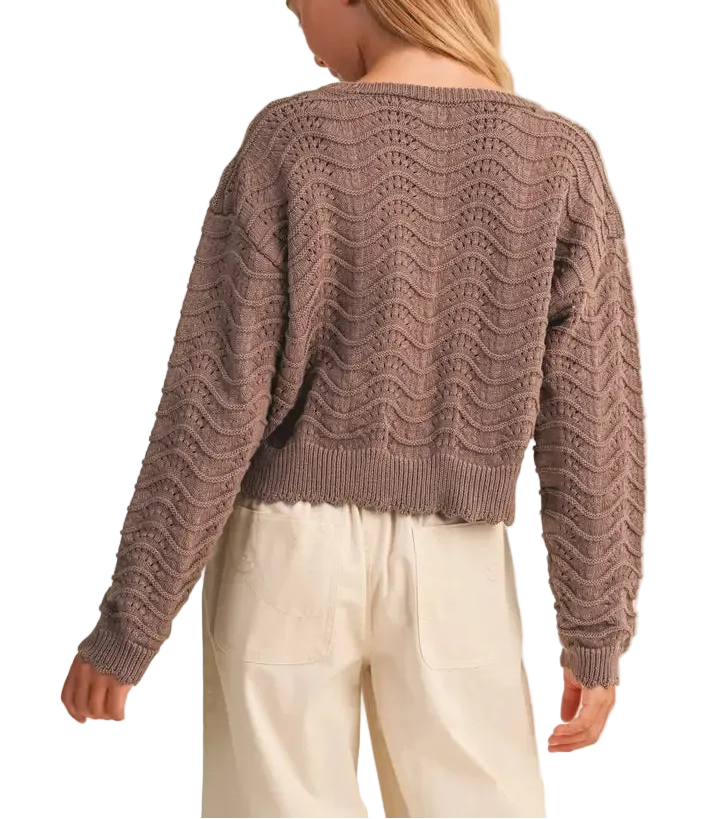 A lightweight pointelle knit sweater featuring an open, fan-and-wave stitch pattern throughout. A round neckline and long sleeves keep the shape simple, while scalloped edging at the hem and cuffs adds a delicate finish. An easy transitional layer with texture and dimension.