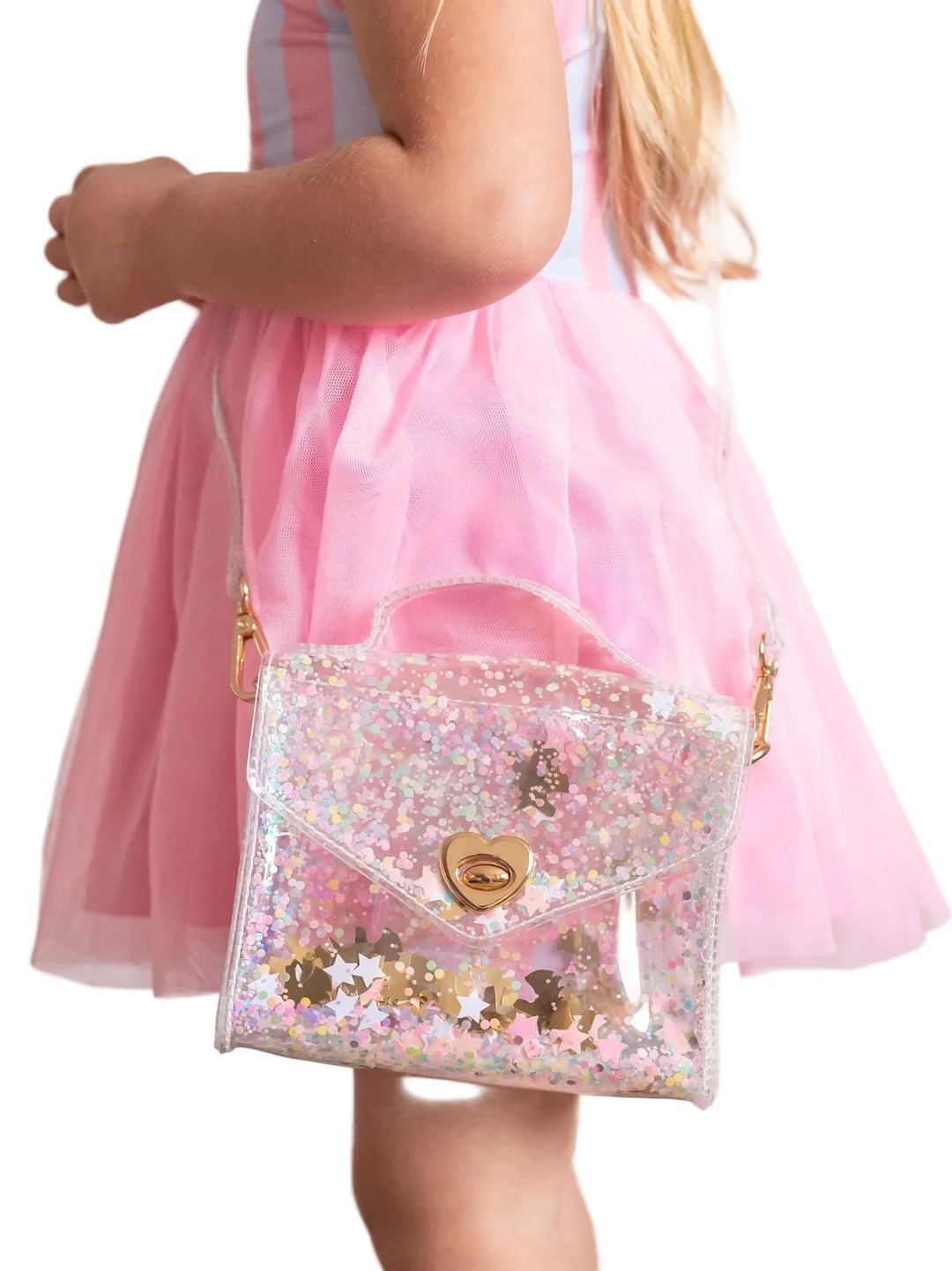 A child wearing a pink tulle dress carries a small clear vinyl shoulder bag covered in iridescent sequins with gold hardware and a heart-shaped clasp.