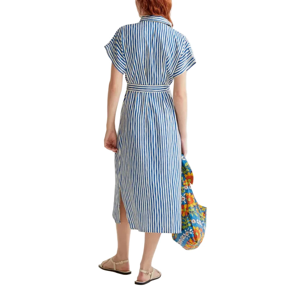 Woman wearing a blue and white striped dress holding a colorful bag on a white background