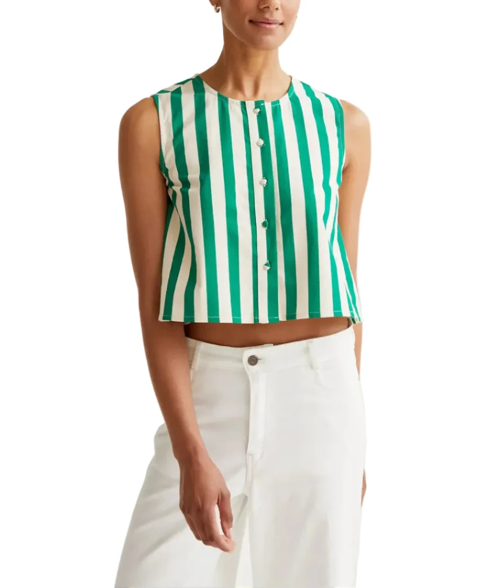 Woman wearing a green and white striped sleeveless top with white pants on a light gray background