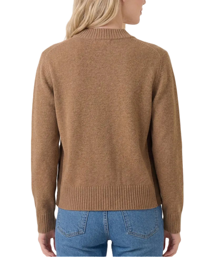 A woman shown from the back wearing a camel brown knit sweater and blue jeans against a light beige studio background.