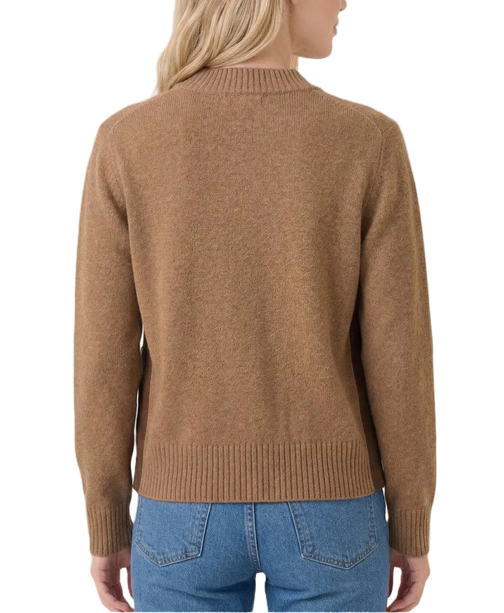 A woman shown from the back wearing a camel brown knit sweater and blue jeans against a light beige studio background.