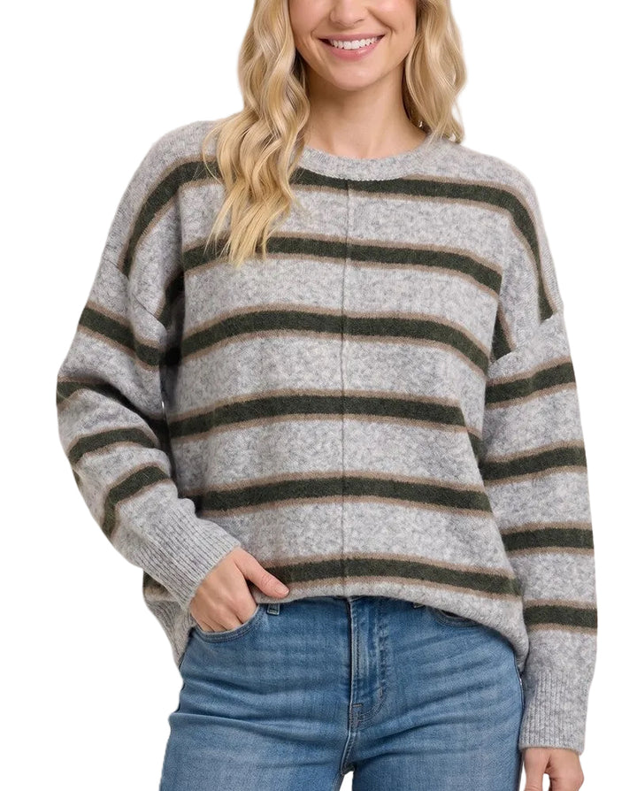 A woman wearing a heather gray knit sweater with horizontal dark olive green stripes, paired with blue jeans, against a solid light beige background.
