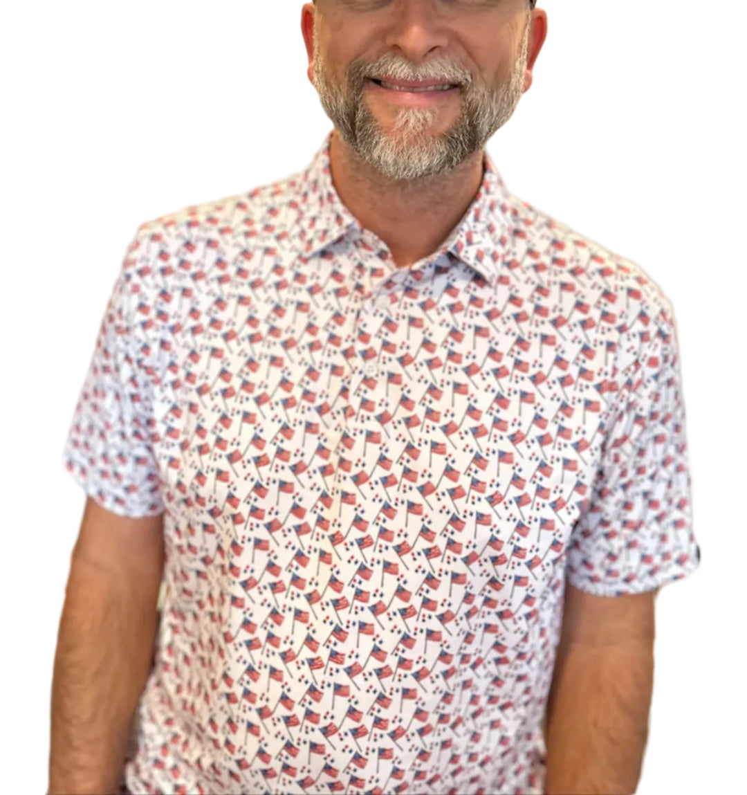 Man wearing a cap with an American flag design and a patterned shirt indoors.