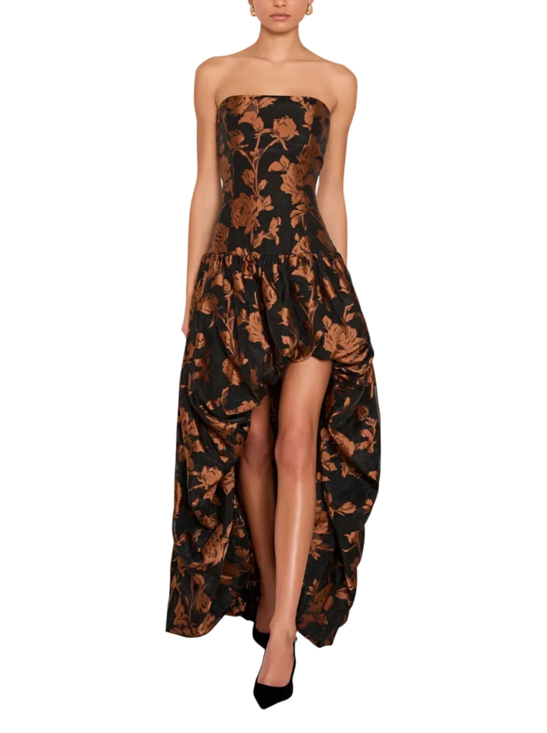 A model wearing a strapless high-low dress with a brown and black floral jacquard pattern, set against a solid light gray background.