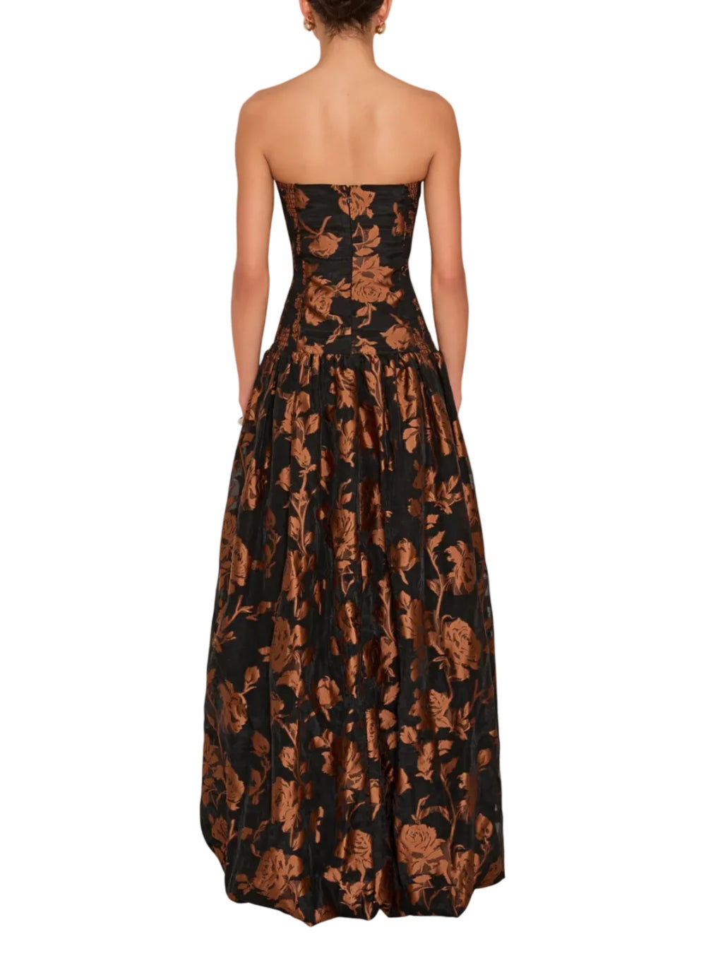 A strapless floor-length gown shown from the back on a model, featuring a black base with a metallic bronze floral pattern.