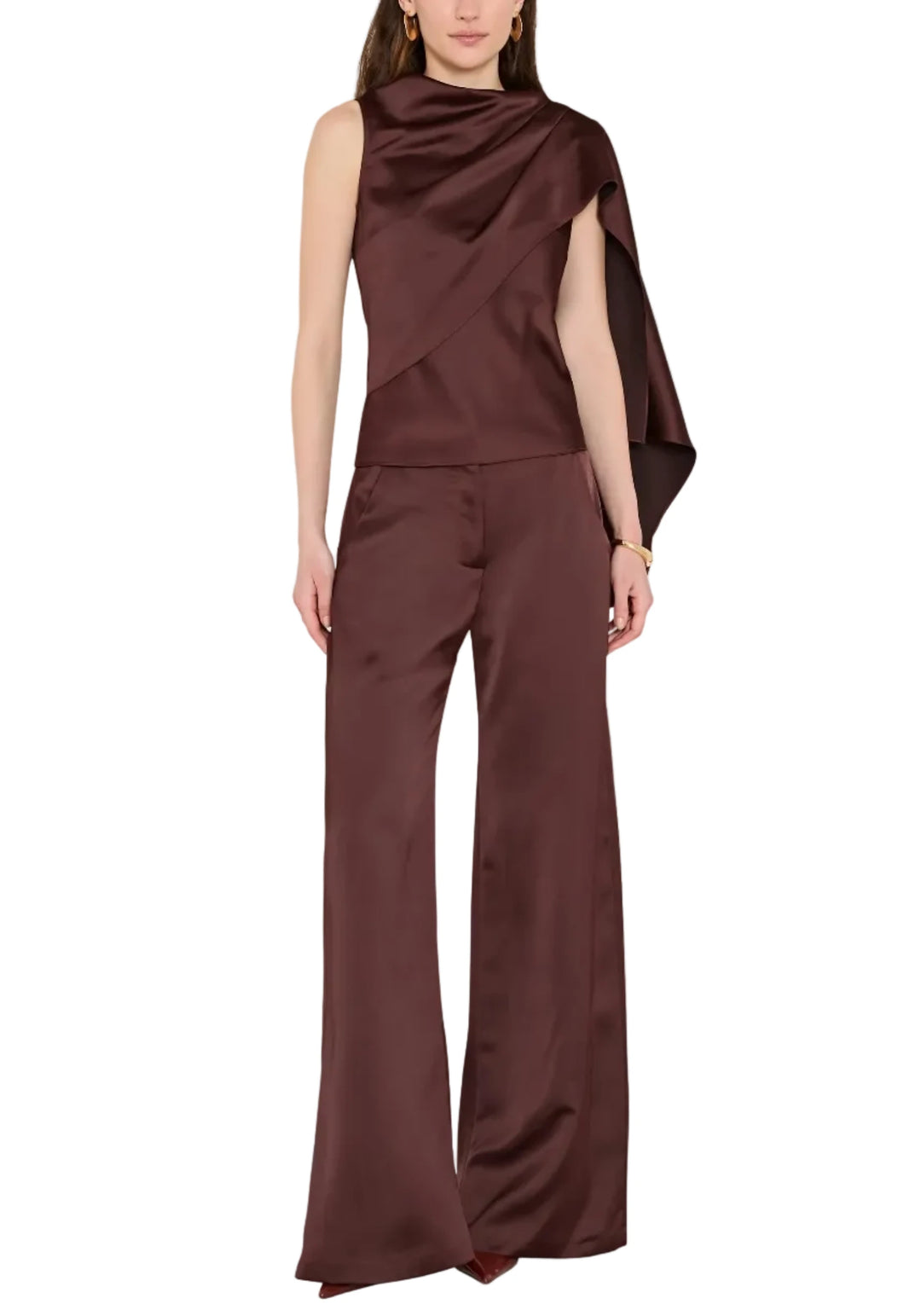 A model wearing a dark brown satin one-shoulder top and matching wide-leg trousers, photographed against a solid light gray background.