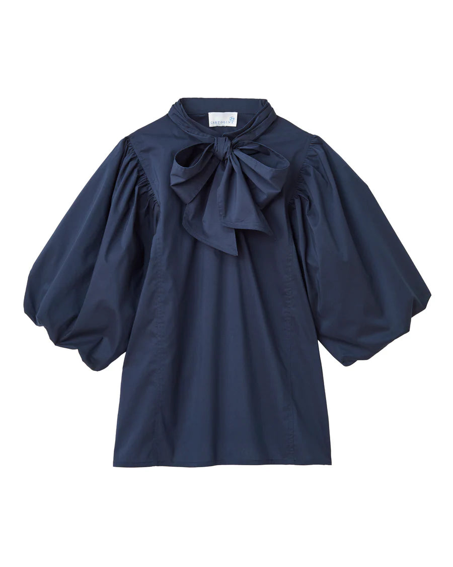 
The Perry Blouse in Midnight Blue—where sculpted sleeves meet soft cotton poplin, and every detail feels thoughtful. It’s the kind of piece that catches the light and lingers in memory.

Sculpted Volume: Puffed sleeves with a rounded bubble hem
Refined Touch: Slit neckline with adjustable closure and removable neck tie
Streamlined Shape: Breathable stretch cotton with a clean, tuckable fit