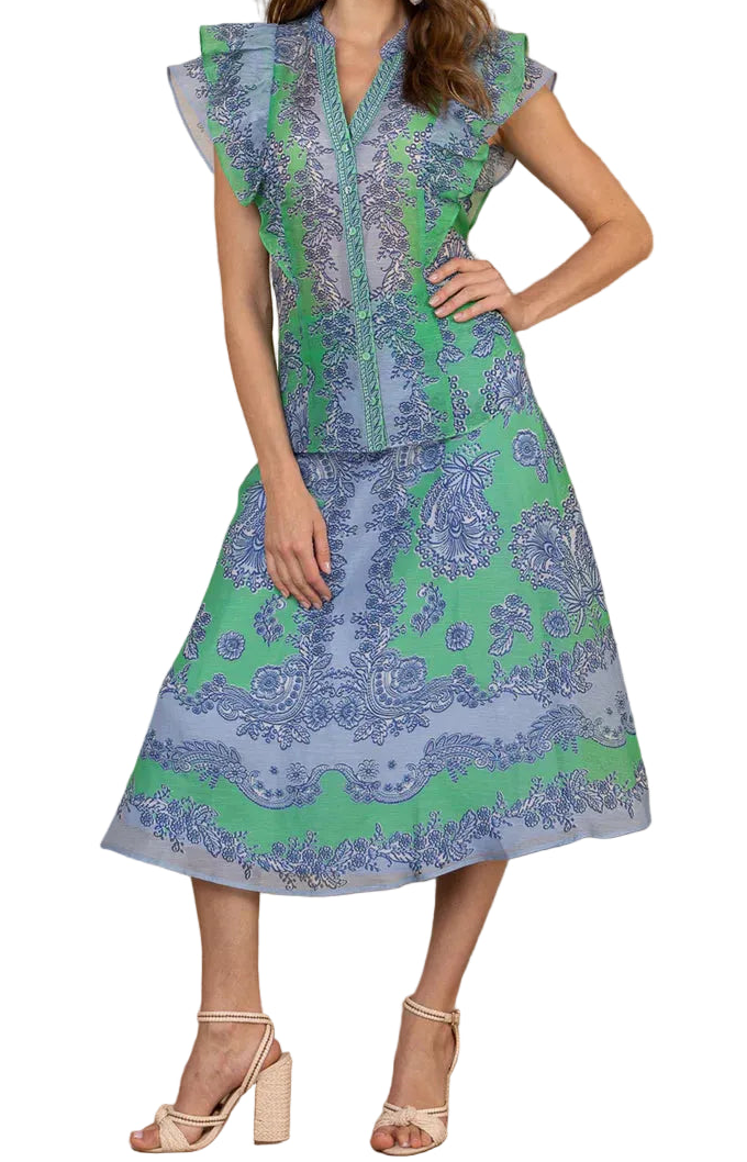 Woman wearing a blue and green patterned dress against a wooden wall.