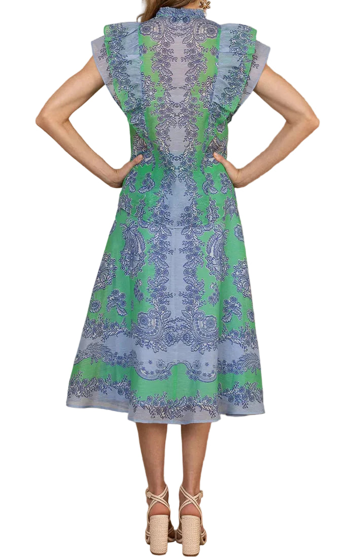 Woman wearing a skit and top with green and blue design against a white background.