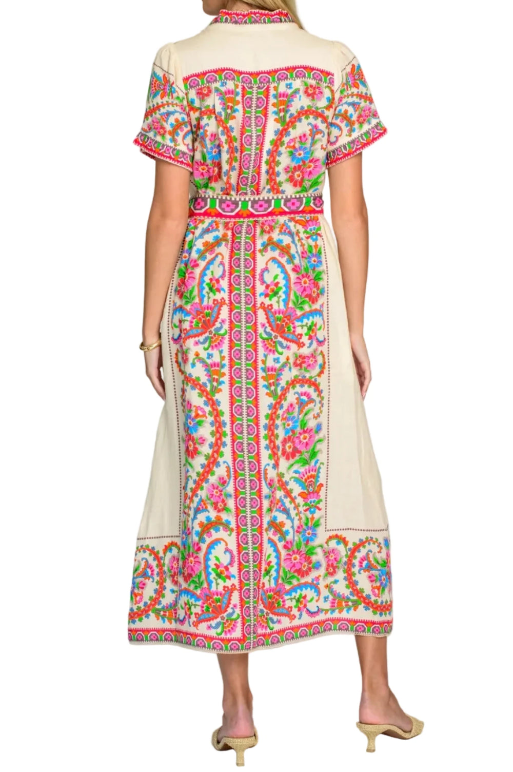 Woman wearing a colorful patterned dress on a plain background