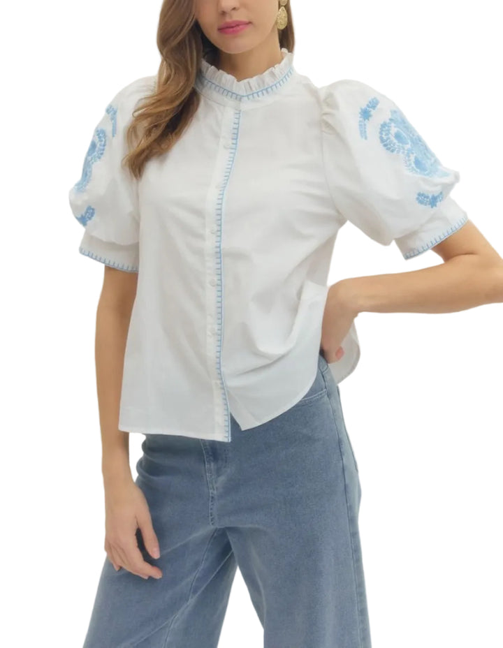Floral embroidered puff short sleeve top featuring ruffled band collar and button closure at front with contrast stitch detail. Unlined. Woven. Non-sheer. Lightweight.
