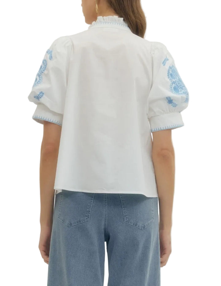 Floral embroidered puff short sleeve top featuring ruffled band collar and button closure at front with contrast stitch detail. Unlined. Woven. Non-sheer. Lightweight.
