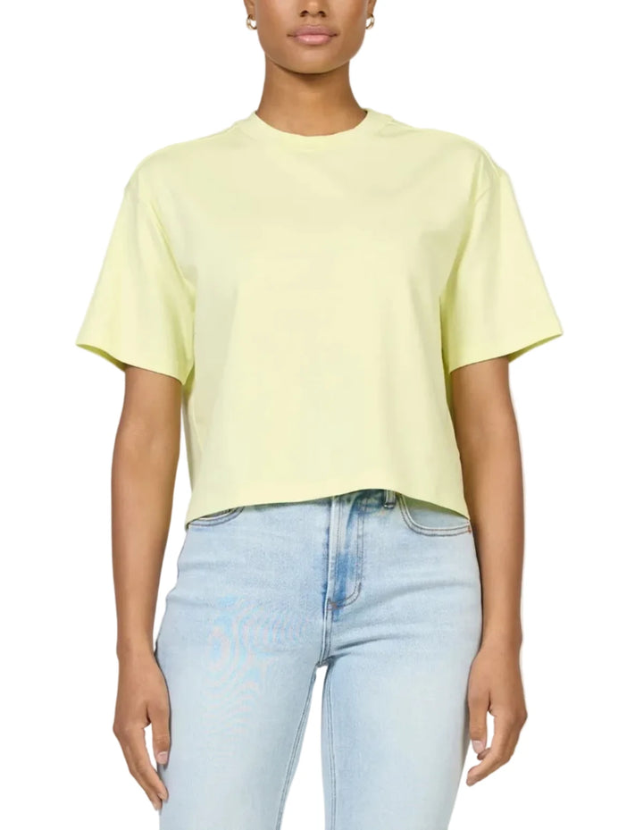 Person wearing a light yellow t-shirt and light blue jeans on a plain background