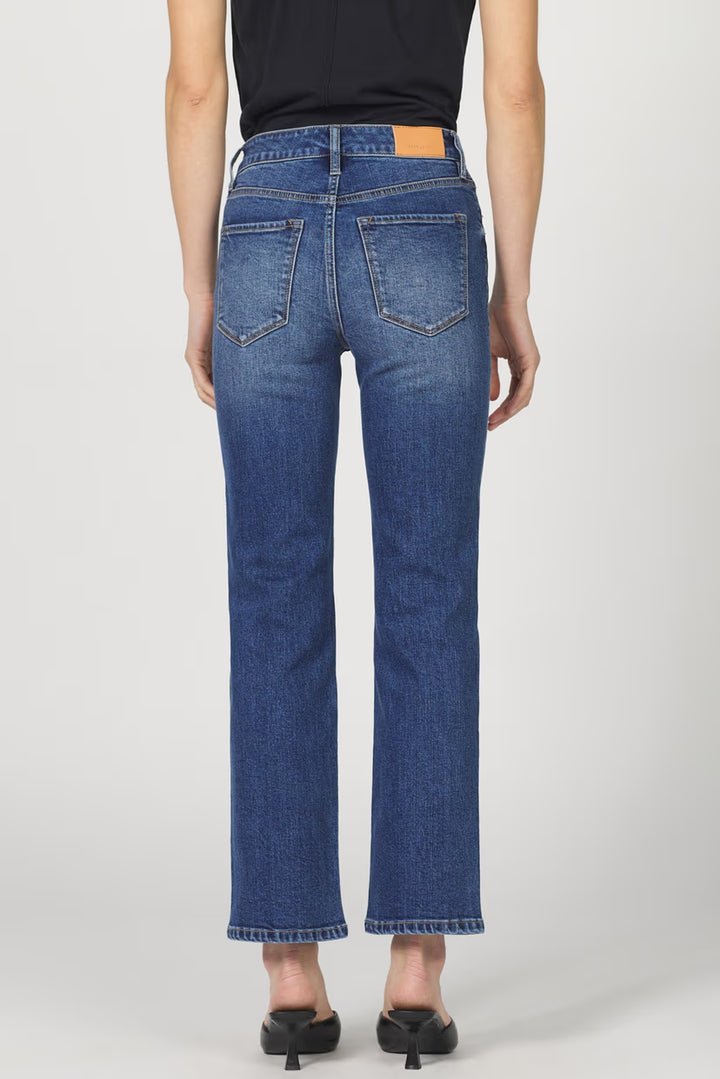Person wearing blue jeans on a plain background