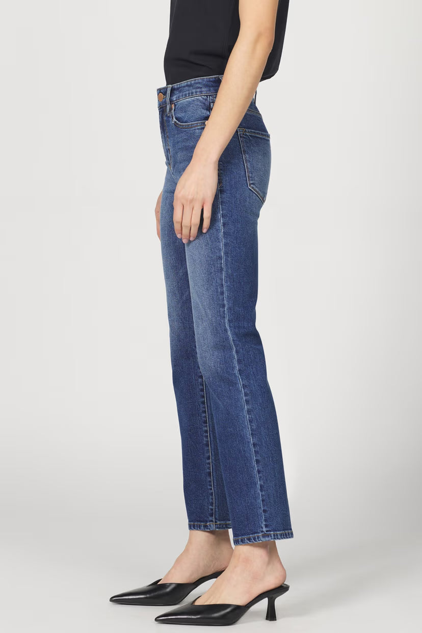 Person wearing blue jeans and black shoes on a white background