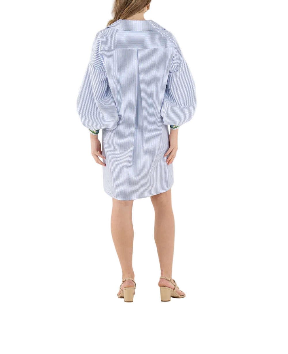 The Iris Oxford Dress puts a bold twist on a classic shirt dress with an intentionally oversized silhouette. Designed with an exaggerated fold collar, dramatic blouson sleeves, and gold button closures, this style feels both modern and polished. Contrasting striped trim at the sleeve cuffs and along the side seams adds a graphic finish. Easy to dress up with heels or keep casual with sneakers, this piece delivers effortless versatility with statement appeal.