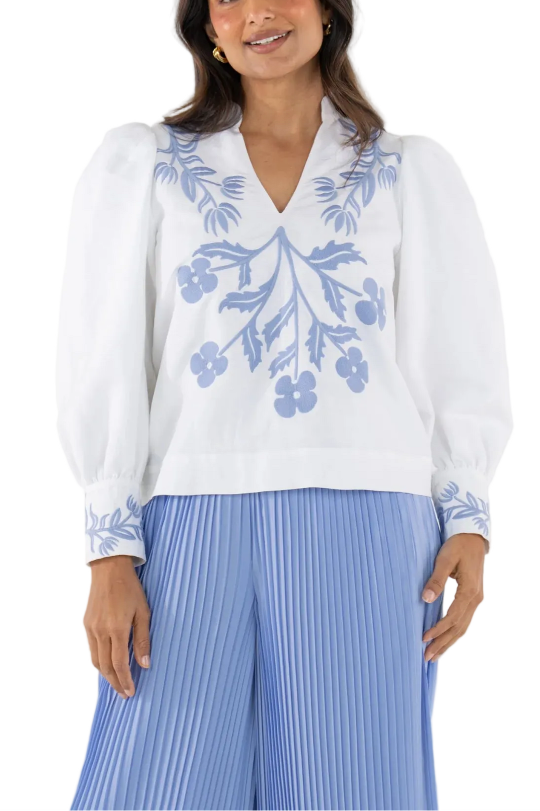 The Hampton Top in Dutch Tile is a natural blend of structure and artistry. Designed with a mandarin-style collar, softly blouson sleeves with cuffed wrists, and a subtly tailored silhouette, it feels polished yet approachable. The placed embroidery reimagines classic floral motifs through the lens of hand-painted ceramic tiles, with intricate stitching that adds depth and a globally inspired, dimensional finish.