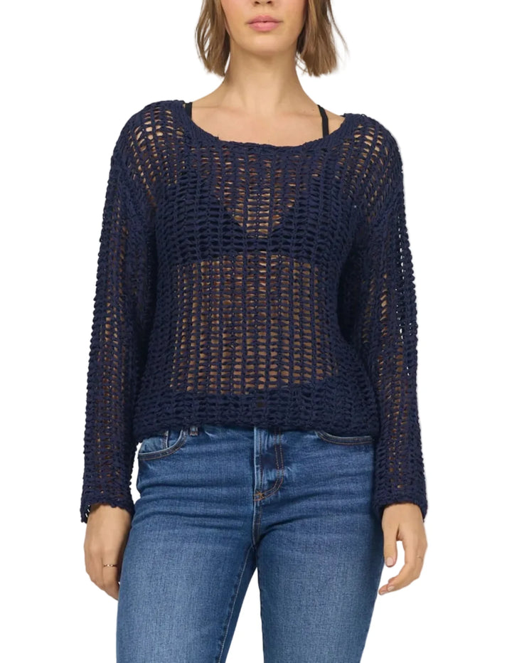 Woman wearing a navy blue crochet top and jeans on a white background