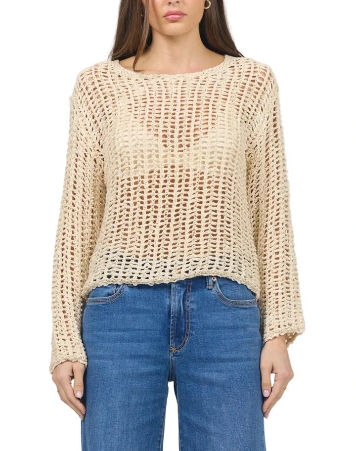 Woman wearing a beige knitted sweater and blue jeans on a plain background