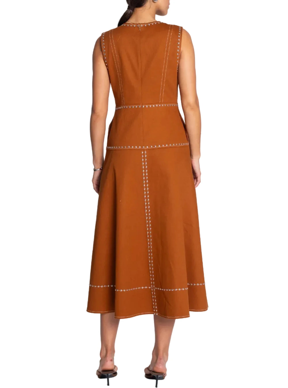 Woman wearing a brown dress with white stitching on a white background